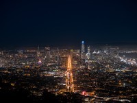 City skyline at night with illuminated streets and tall buildings.